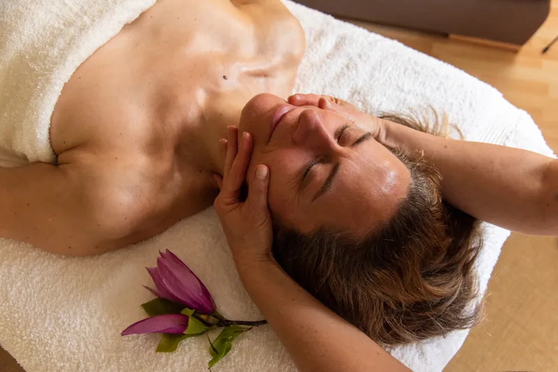 Kundin genießt eine entspannende Gesichtsmassage.